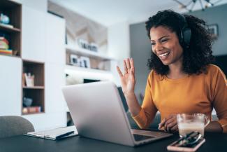 A woman sits at a laptop wearing headphones